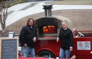 Jonathan and Sarah standing in front of their woodfired oven